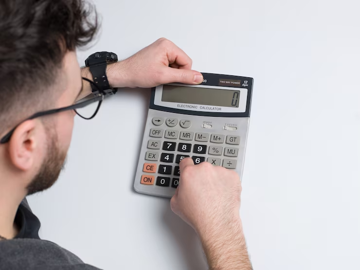 A man with glasses using a calculator
