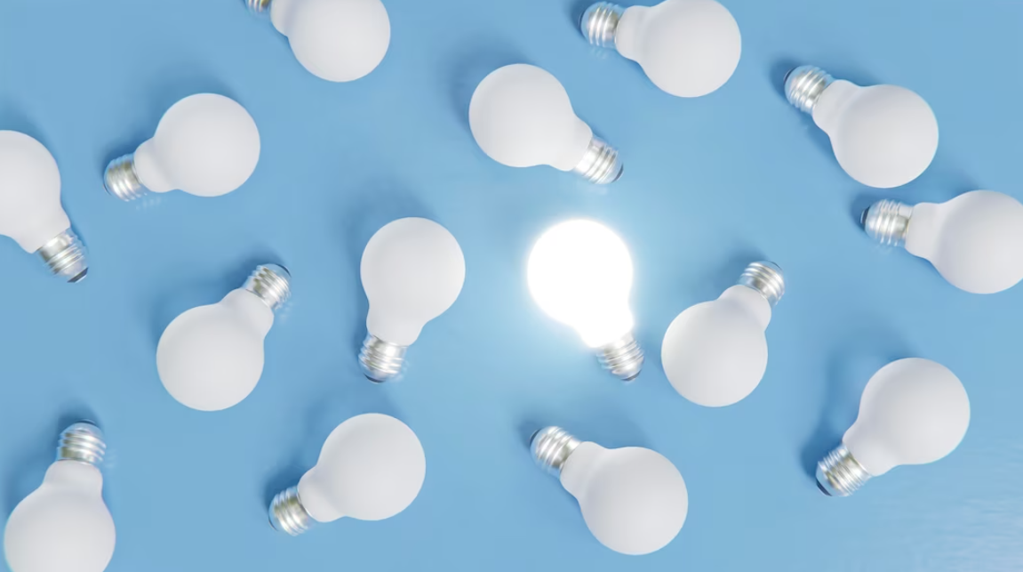 white light bulbs, one is on - on plain blue background