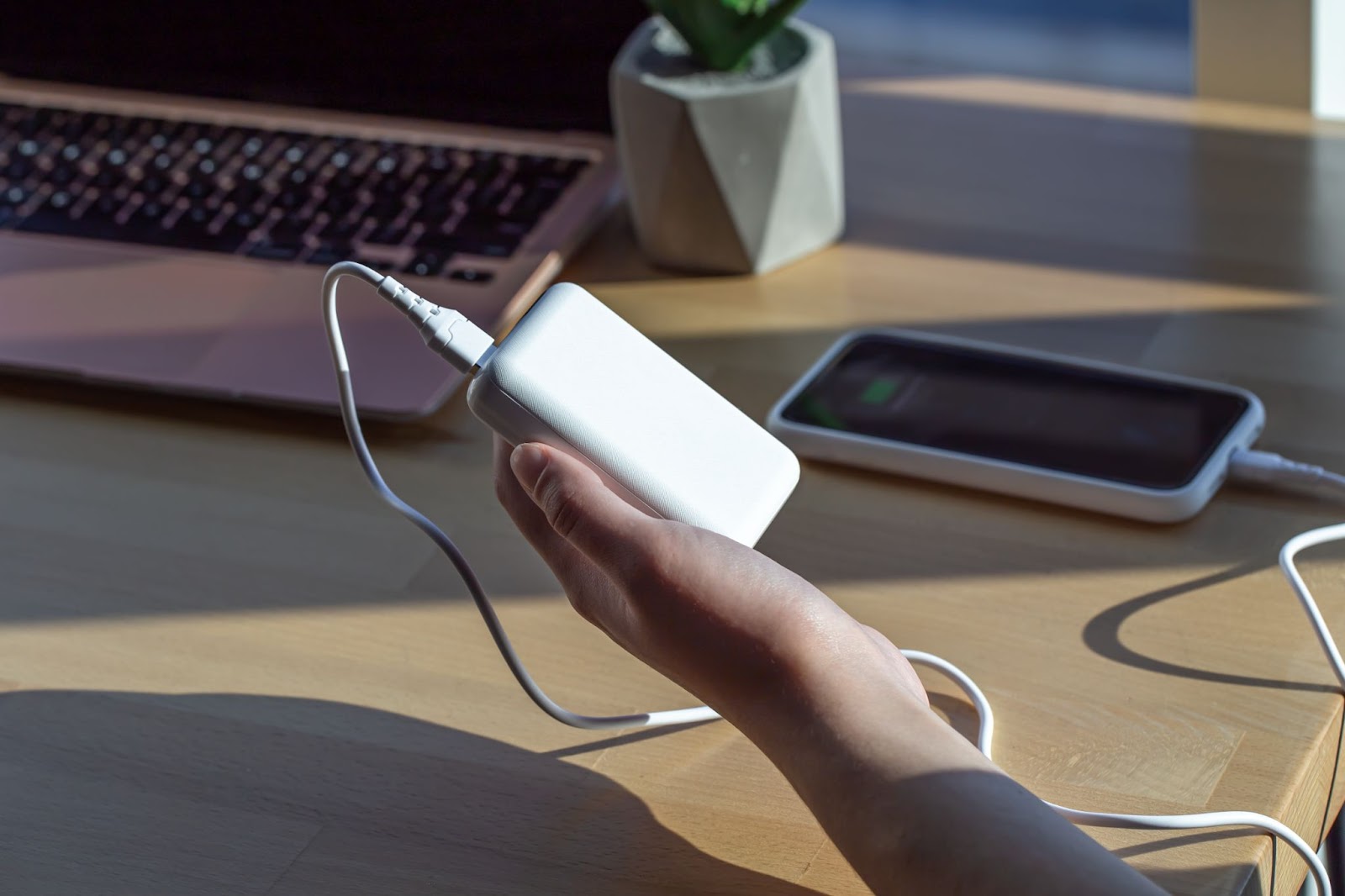 a small white power bank in a woman's hand